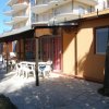 Terrazza esterna con tavoli bianchi vicino a un edificio.