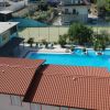Vista dall'alto di una piscina accanto a edifici con tetto in tegole rosse, vicino a campi sportivi.