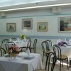 Sala ristorante con tavoli apparecchiati e quadri alle pareti.