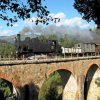 Treno a vapore attraversa un ponte di pietra.