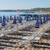 Sedie e ombrelloni blu su una spiaggia sabbiosa.
