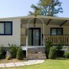 Casa mobile con veranda coperta, circondata da prato e piante.