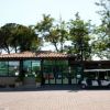 Struttura con tetto in tegole e golf cart bianco parcheggiato, con alberi sullo sfondo.