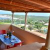 Terrazza coperta con tavolo apparecchiato, vista su mare e colline.