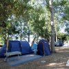 Tende blu in un bosco con tavolo picnic.