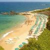 Spiaggia con ombrelloni, mare e scogli.