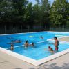 Piscina all'aperto con adulti e bambini che nuotano.