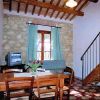Sala con parete in pietra, tavolo, sedie, divano, finestra con tende, e scala in legno.
