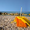 Lettino giallo e arancione su spiaggia di ciottoli.