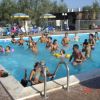 Persone che si divertono in una piscina all'aperto, circondati da ombrelloni gialli.