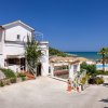 Casa bianca vicino al mare con alberi e cielo blu.