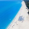 Lunga spiaggia con ombrelloni e mare blu.