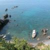 Spiaggetta con barche ormeggiate e acque limpide, circondata da rocce.
