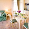 Sala con cucina, tavolo e quattro sedie, divano verde.