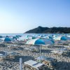 Ombrelloni blu e bianchi su una spiaggia sabbiosa.