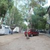 Auto e caravan vicino a un edificio, alberi sullo sfondo.