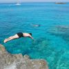 Persona tuffa in mare cristallino.