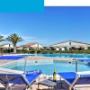 Piscina con lettini e tavolino, circondata da palme.