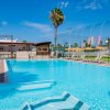 Piscina azzurra, sdraio e ombrelloni, cielo sereno.