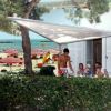 Persone sedute a un tavolo esterno vicino alla spiaggia con ombrelloni.