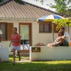 Due bambini corrono vicino a un bungalow, coppia seduta sul muretto.