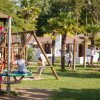Parco giochi per bambini con altalene e palme.
