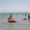 Famiglie che giocano in mare con gonfiabili colorati.