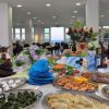 Tavolo buffet con cibo e decorazioni floreali.