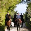 Persone a cavallo su un sentiero circondato da alberi verdi.