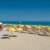 Spiaggia con ombrelloni gialli e cabine.