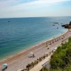 Spiaggia di ciottoli con ombrelloni e scogli.