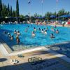 Piscina all'aperto affollata di persone che nuotano.