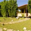 Un giardino ben curato con viali in pietra e una piccola struttura gialla tra gli alberi.