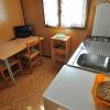 Cucina compatta con lavandino, fornelli, tavolo e sedie, illuminata da una finestra.