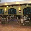 Interno di un caffè con sedie in stile bistrot, finestre grandi e luci soffuse.