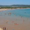 Spiaggia affollata con bagnanti e mare calmo.