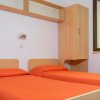 Due letti singoli con copriletto arancione in una stanza luminosa.