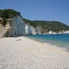 Spiaggia tranquilla con ciottoli bianchi, scogliera bianca e mare blu limpido.