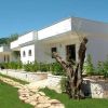 Bungalow bianchi con un giardino verde e un sentiero di pietra di giorno.