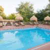 Piscina esterna con lettini e ombrelloni di paglia.