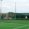 Due persone giocano a tennis su un campo all'aperto.