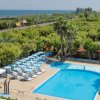 Una piscina con lettini, circondata da alberi.
