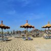 Spiaggia con lettini e ombrelloni di paglia.