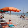Spiaggia con ombrelloni arancioni e sedie a sdraio vicino al mare.