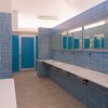 Bagno con piastrelle blu, lavandini e specchi allineati.