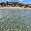 Spiaggia con ombrelloni di paglia e mare trasparente.