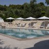 Piscina con lettini bianchi e ombrelloni, circondata da un muro di pietra.