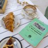Colazione con dolci e libro su tavolo bianco.