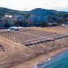 Spiaggia con ombrelloni e vista su colline e edifici.