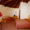 Camera da letto con tetto in legno, due letti e arredamento in vimini.
